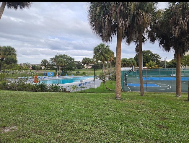 view of swimming pool featuring a yard and basketball hoop