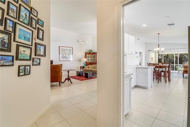 corridor featuring lofted ceiling, light tile patterned floors, and an inviting chandelier