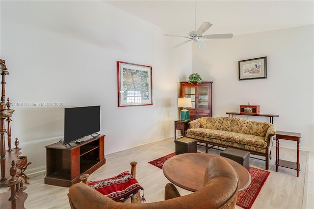 living room with ceiling fan, vaulted ceiling, and light wood-type flooring