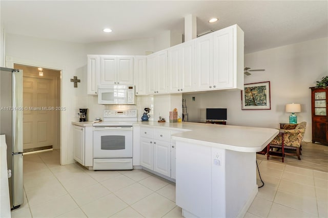 kitchen with white appliances, kitchen peninsula, white cabinets, and light tile patterned flooring