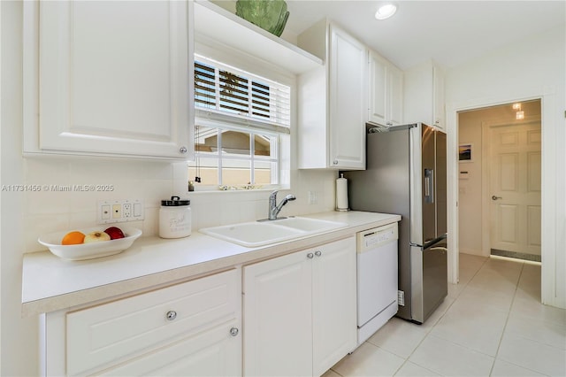 kitchen with sink, light tile patterned floors, white cabinetry, white dishwasher, and tasteful backsplash