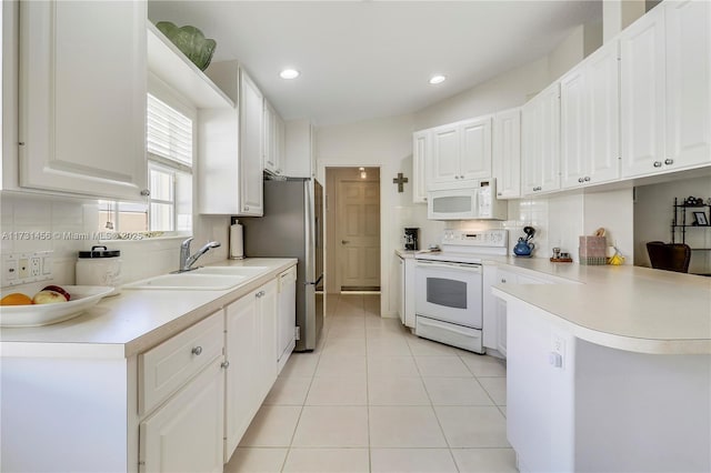 kitchen with light tile patterned flooring, sink, white cabinets, kitchen peninsula, and white appliances