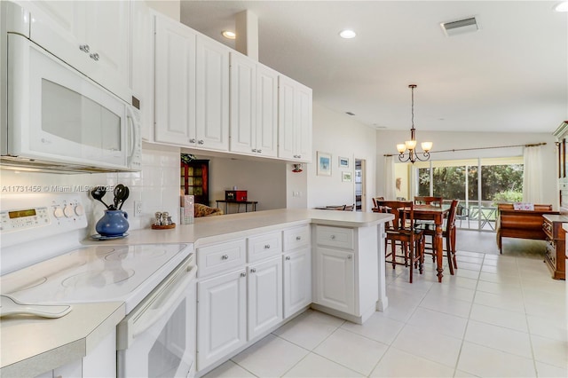 kitchen with vaulted ceiling, kitchen peninsula, pendant lighting, white appliances, and white cabinets