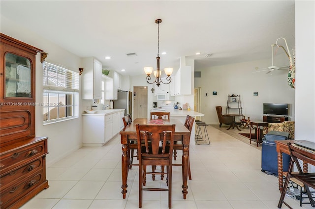 dining space with light tile patterned flooring, sink, and ceiling fan with notable chandelier