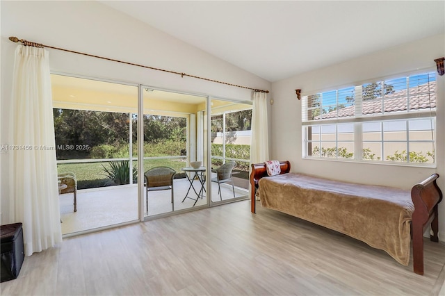 bedroom with lofted ceiling, access to exterior, and light hardwood / wood-style flooring