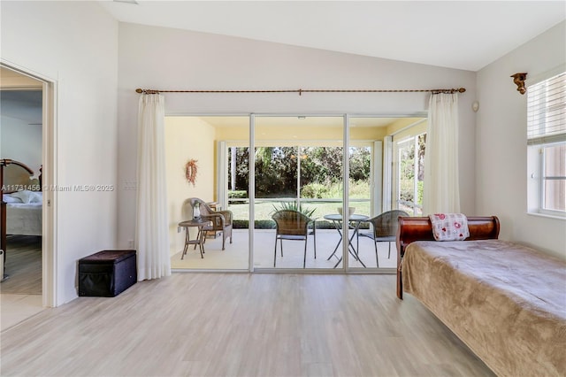 bedroom featuring lofted ceiling, access to exterior, and light hardwood / wood-style floors