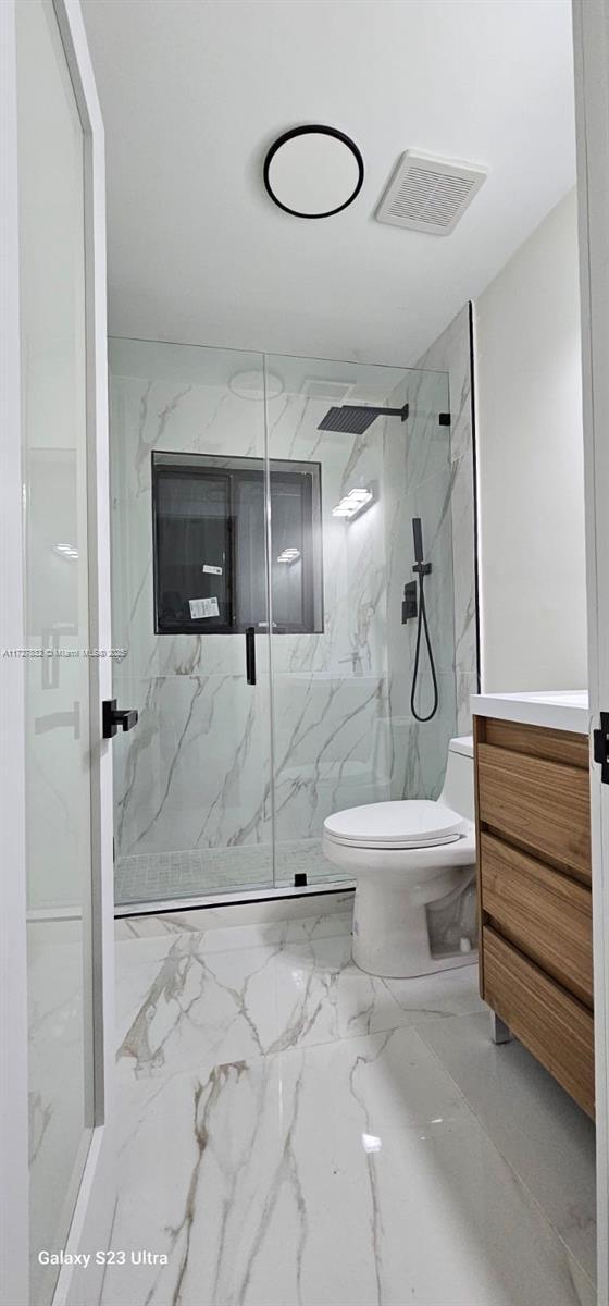 bathroom with vanity, toilet, and a tile shower