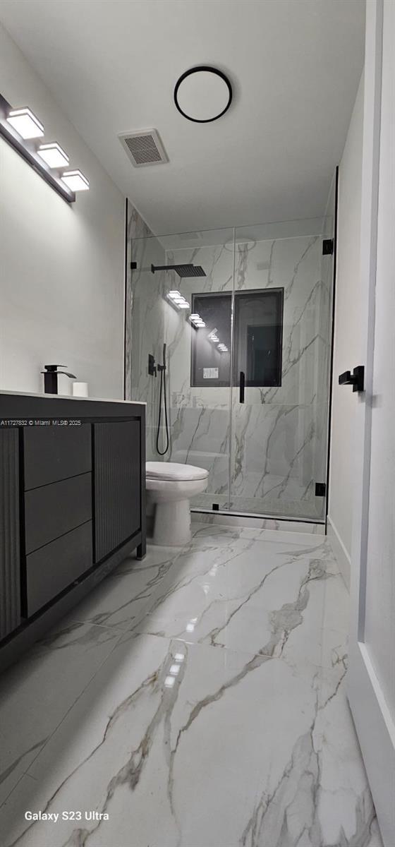 bathroom with toilet and a shower with shower door