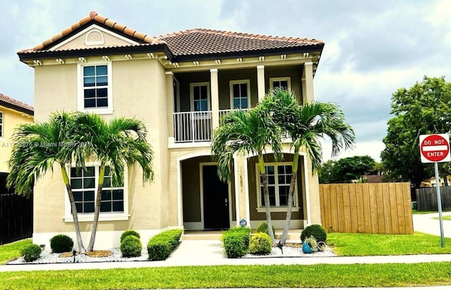 view of front of house with a tiled roof, fence, a front lawn, and stucco siding