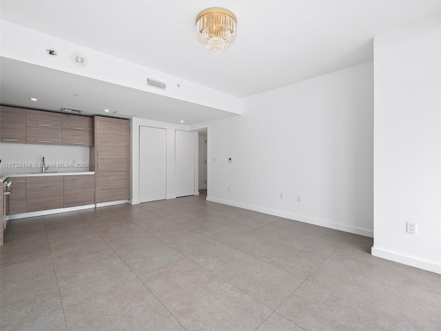 unfurnished living room with sink and a chandelier