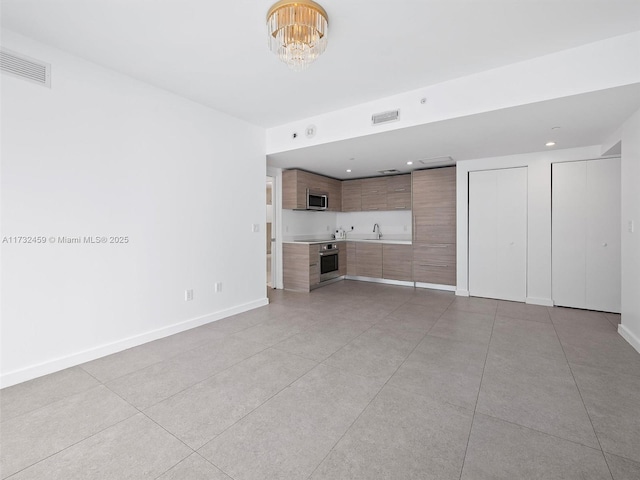 unfurnished living room featuring sink and a notable chandelier