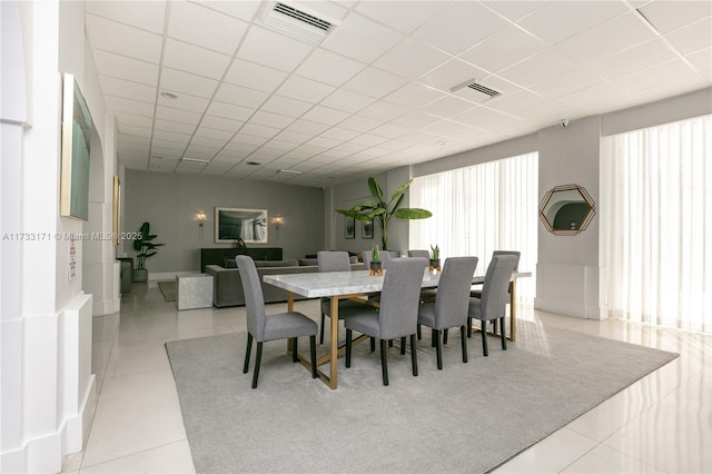 dining space featuring a paneled ceiling and light tile patterned floors