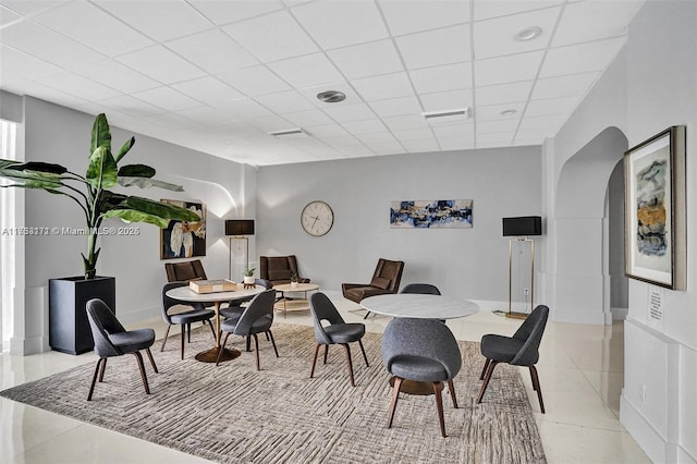 dining room with a drop ceiling and light tile patterned flooring