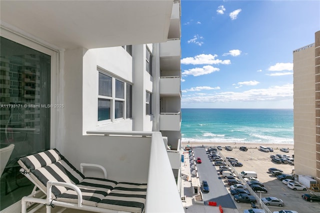 balcony featuring a water view and a beach view