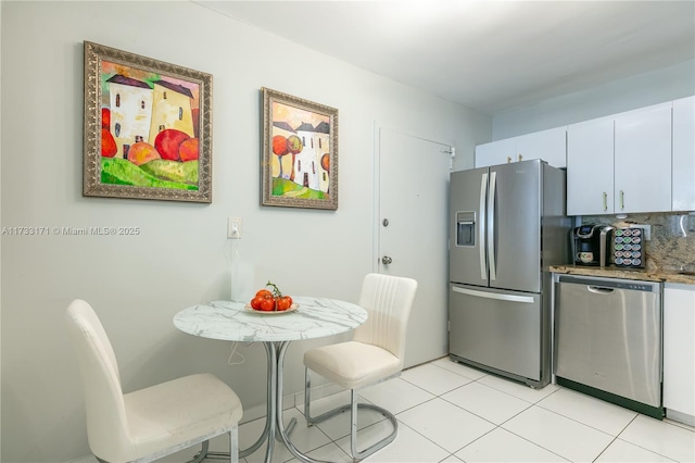 kitchen with stone counters, light tile patterned flooring, appliances with stainless steel finishes, and white cabinets