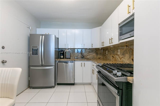 kitchen with appliances with stainless steel finishes, white cabinetry, sink, backsplash, and light tile patterned floors