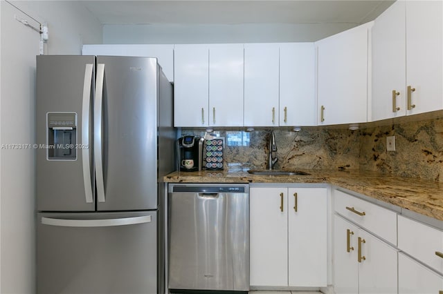 kitchen with dark stone countertops, stainless steel appliances, backsplash, and white cabinets