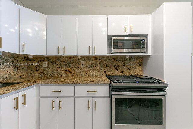 kitchen with white cabinetry, decorative backsplash, stone counters, and appliances with stainless steel finishes