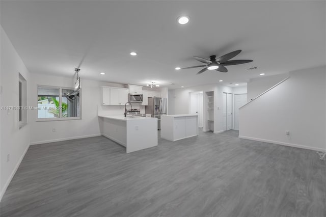 kitchen with white cabinetry, stainless steel appliances, dark hardwood / wood-style flooring, and kitchen peninsula