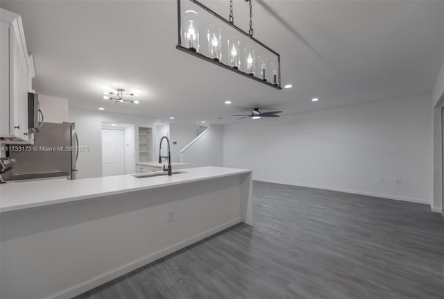 kitchen featuring dark wood-type flooring, sink, decorative light fixtures, range, and white cabinets