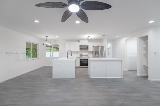 kitchen with sink, a center island, hanging light fixtures, stainless steel appliances, and white cabinets