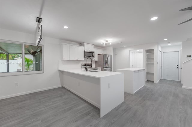 kitchen featuring a kitchen island, decorative light fixtures, white cabinets, kitchen peninsula, and stainless steel appliances