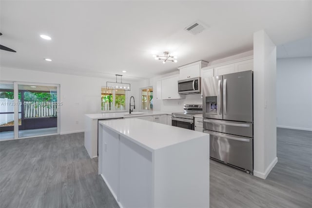 kitchen with a kitchen island, pendant lighting, sink, white cabinets, and stainless steel appliances