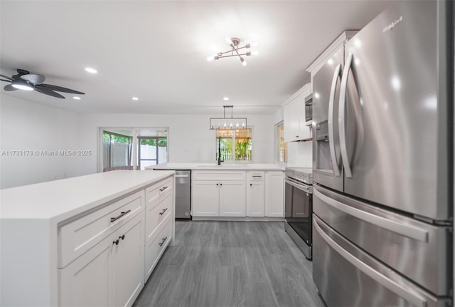 kitchen with dark wood-type flooring, white cabinetry, hanging light fixtures, appliances with stainless steel finishes, and kitchen peninsula