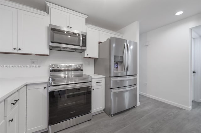 kitchen with light hardwood / wood-style flooring, white cabinets, and appliances with stainless steel finishes