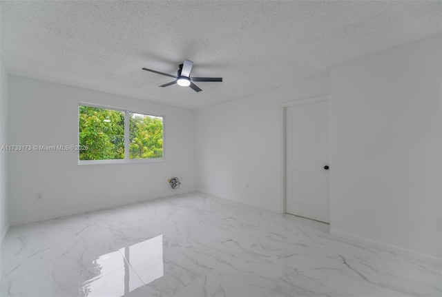 empty room with ceiling fan and a textured ceiling