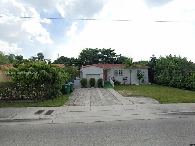 mediterranean / spanish house with a garage and a front lawn