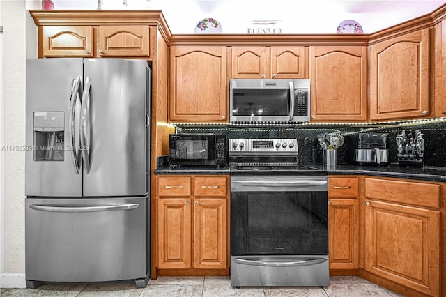 kitchen featuring light tile patterned flooring, stainless steel appliances, and dark stone countertops