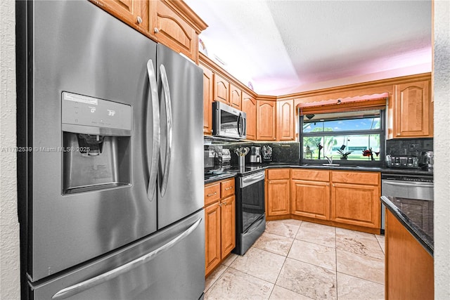 kitchen featuring sink, light tile patterned floors, dark stone countertops, appliances with stainless steel finishes, and decorative backsplash