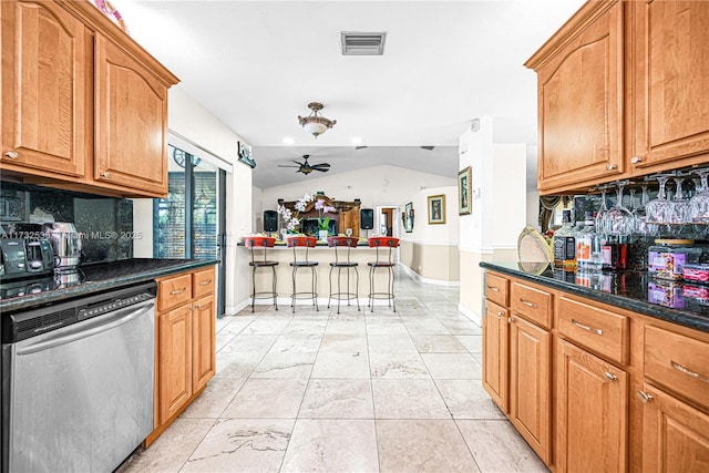 kitchen with vaulted ceiling, dark stone countertops, stainless steel dishwasher, ceiling fan, and backsplash