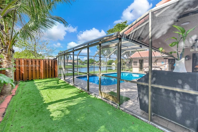 view of pool with a water view, a yard, a patio, and glass enclosure