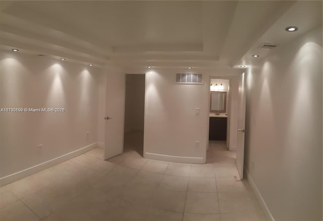 hallway featuring light tile patterned floors and a tray ceiling