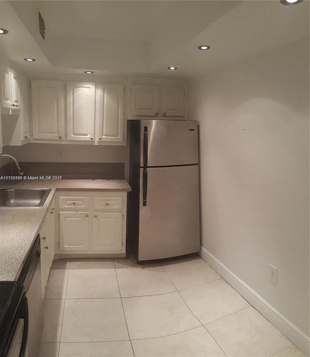 kitchen with light tile patterned flooring, sink, black / electric stove, stainless steel fridge, and white cabinets