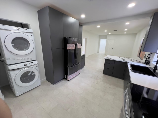 laundry area with stacked washer and clothes dryer and sink