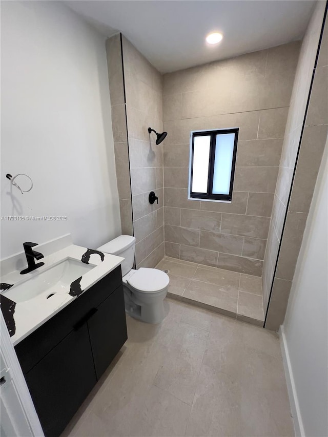 bathroom with vanity, toilet, and a tile shower