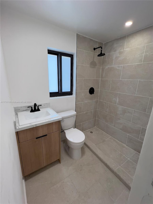 bathroom with vanity, a tile shower, and toilet