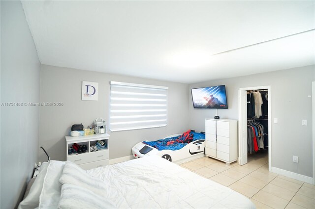 tiled bedroom with a walk in closet and a closet