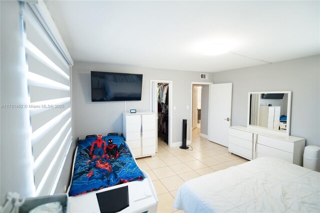 tiled bedroom featuring a walk in closet and a closet