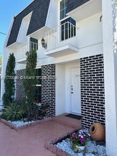 entrance to property with a balcony and a shingled roof