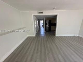 spare room featuring visible vents, baseboards, and wood finished floors