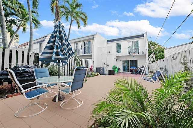 view of patio featuring a balcony, outdoor dining area, a fenced backyard, and cooling unit