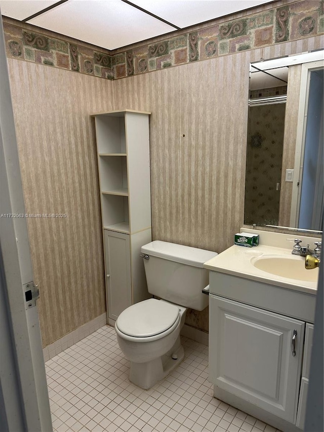 bathroom featuring tile patterned floors, vanity, toilet, and a shower