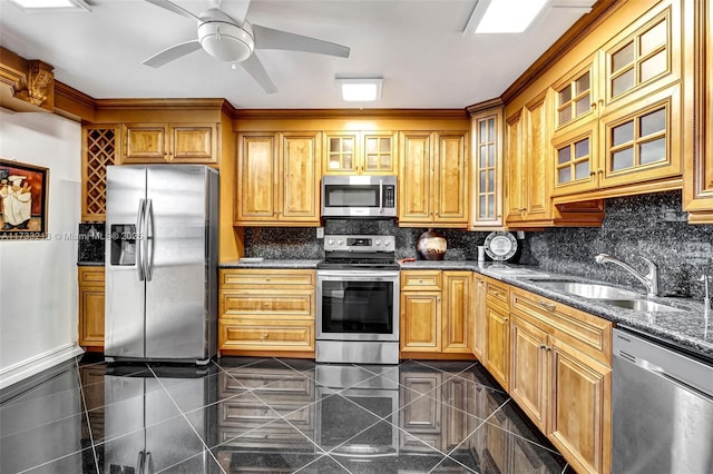 kitchen with dark stone countertops, sink, stainless steel appliances, and ceiling fan