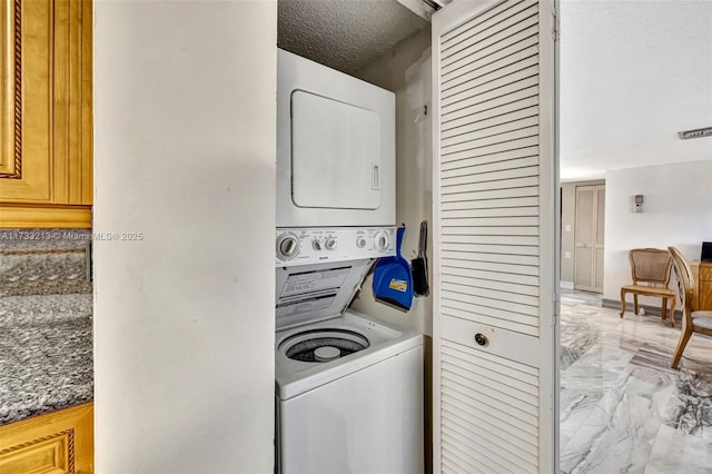 laundry room featuring stacked washer / drying machine and a textured ceiling