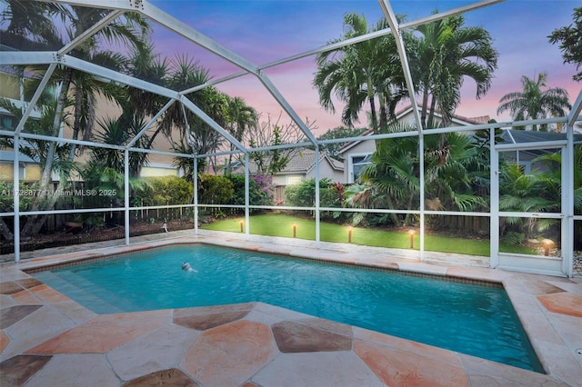 pool at dusk featuring a patio and glass enclosure