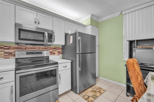 kitchen featuring light tile patterned flooring, tasteful backsplash, white cabinetry, ornamental molding, and stainless steel appliances